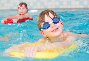Kinder mit Schwimmbrettern in einem Schwimmbad