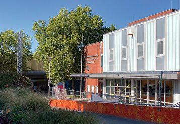 Außenansicht der Freizeitstätte Garath, Bauzaun davor, sommerlich