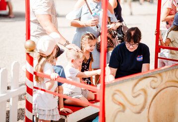Gruppe von Kindern umgeben von Erwachsenen