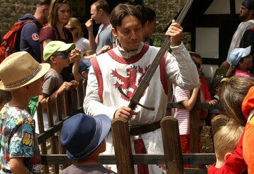 Georgs Ritter zeigt auf Schloss Burg Kindern sein Schwert