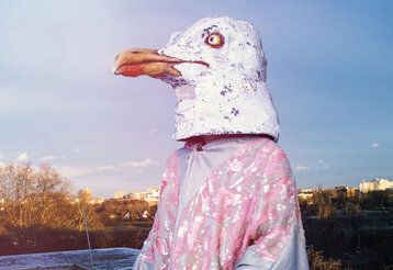 Schasuspieler mit Pinguinmaske, im Hintergrund Hochhäuser