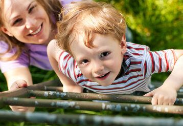 Kind klettert Leiter hoch Mutter hält Leiter fest