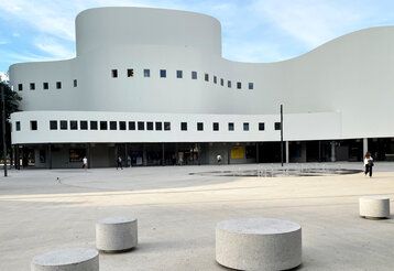 weißes geschwungenes Gebäude mit Platz davor