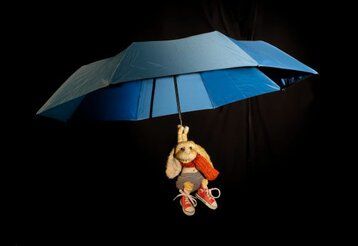 Eine Hasenpuppe schwebt an einem offenen Regenschirm