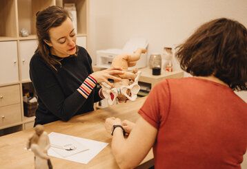 Eine Frau erklärt einer anderen Frau den Geburtsvorgang an Hand eines Modells mit einer Puppe