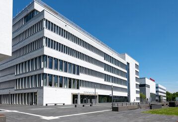 Gebäudekomplex von außen bei schönem Wetter, blauer Himmel