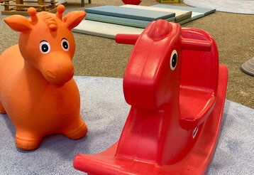 eine orange Hüpfkuh und ein rotes Schaukeltier, Indoorspielplatz Rheinkirche