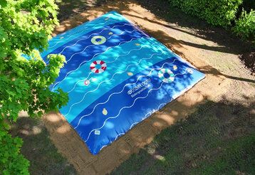 ein großes Hüpfkissen auf einer Wiese in einem Düsseldorfer Freibad