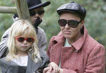 eine Mutter und zwei Kinder gucken grimmig in die Kamera, alle tragen Sonnenbrillen, ein Kind hält eine Spielzeugpistole in der Hand