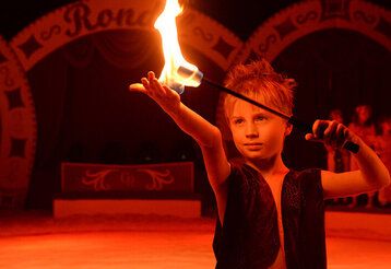 Junge mit Feuerstab im Winterzirkus