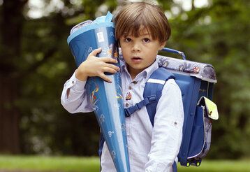 Junge mit blauer Schultüte im Park