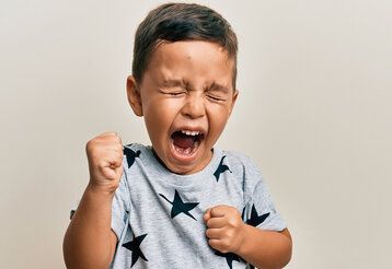 kleiner Junge schreit wütend mit geballten Fäusten