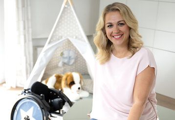 Porträt von Karoline Peter, im Hintergrund ein Spielzelt mit Plüschhund und ein Kinderrollstuhl