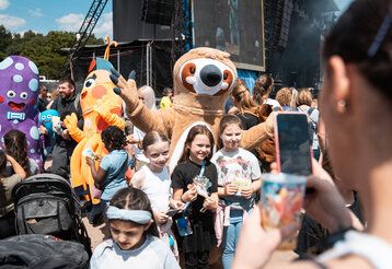 Katta-Figuren posieren mit Zuschauerinnen fürs Foto beim Katta Festival