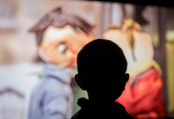 Kikife Silhouette eines Kinderkopfes vor Kino-Leinwand