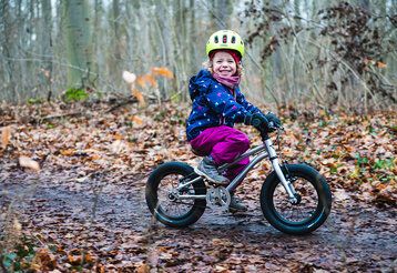 kind mit kinderfahrrad im wald