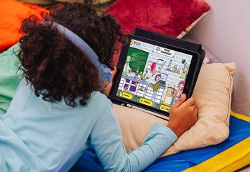 Kind liegt mit Tablet auf einer Matratze und betrachtet Kinderwebsite Crocos Geheimlabor