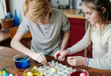 ein Junge und ein Mädchen färben Ostereier