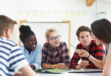 Zwei Jungs und drei Mädchen sitzen zusammen in einer Besprechung