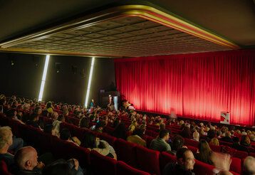 Kinosaal mit Zuschauern während der Kurzfilmtage Oberhausen, roter Vorhang geschlossen