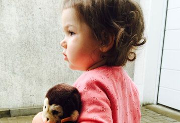 Kleinkind mit Stofftier-Äffchen wartet auf die Eltern