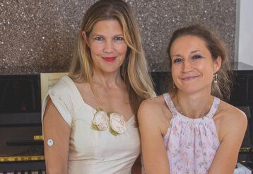 Porträt von Irina Buch und Caroline, beide sitzen nebeneinander vor einem Klavier