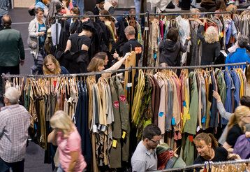 Kleiderständer mit Kostümen, Leute stöbern, von oben fotografiert