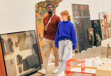 ein junger Mann und eine junge Frau laufen durch einen Raum mit Kunstwerken