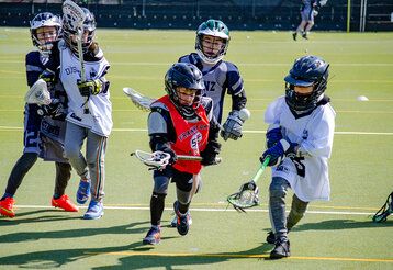 Fünf Kinder spielen Lacrosse