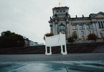 überdimensionale leere Wiege steht vor dem Berliner Reichstagsgebäude