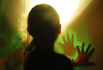 Ein Mädchen legt ihre Hände auf eine Wand mit bunten Lichtinstallationen