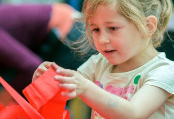 Mädchen spielt mit rotem Band