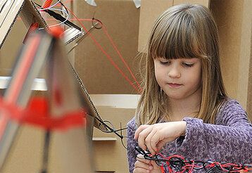 Mädchen bastelt mit Kabelbindern und Pappe