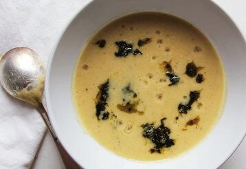 weißer Porzellanteller mit Suppe von oben fotografiert, daneben liegt ein Löffel
