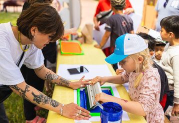 Mädchen macht Siebdruck an einem Stand beim Mitmachfestival Konferenz der Kinder
