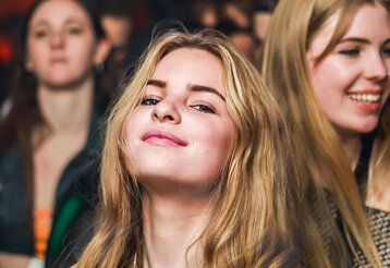 Teenie-Mädchen guckt selbstbewusst in die Kamera, im Hintergrund andere Mädchen