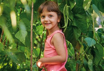 Mädchen im Gebüsch vom Gemüsegarten