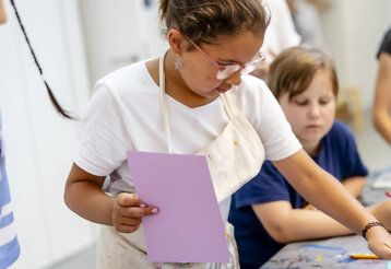 Mädchen arbeitet in Druckwerkstatt, andere Kinder gucken zu