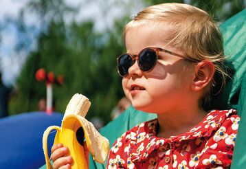 Porträt eines Mädchens mit Sonnenbrille und Banane
