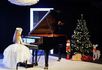 Mädchen spielt Klavier, die Bühne ist weihnachtlich dekoriert