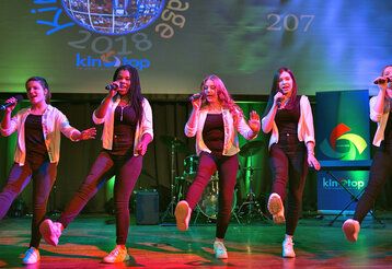 Fünf Mädchen tanzen und singen auf einer Bühne