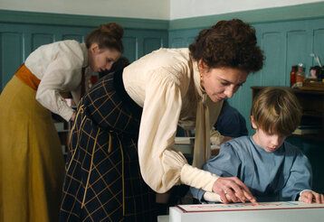 Maria Montessori hilft einem Schüler beim Lernen