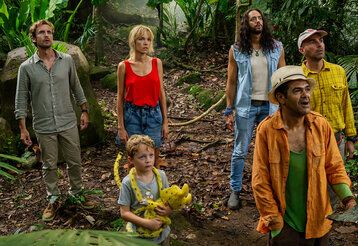 Szene aus dem Film Marsupilami, vier Erwachsene und ein Kind mit Marupilami-Plüschtier stehen in einem Urwald und gucken nach oben