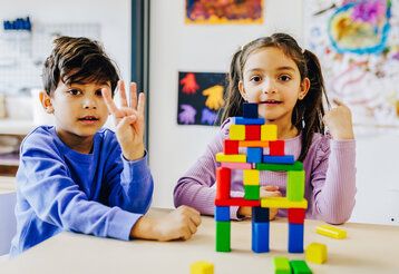 ein Junge und ein Mädchen sitzen am Tisch und haben Bauklötze gestapelt