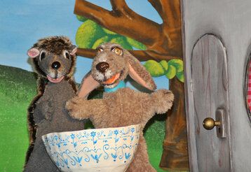 Igel- und Hund-Handpuppen mit einer Schale auf Puppenbühne