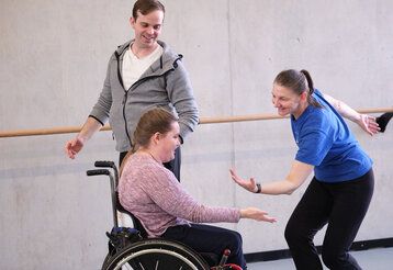Drei Personen tanzen, eine sitzt dabei im Rollstuhl