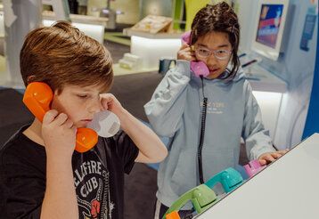 Zwei Kinder telefonieren mit bunten Telefonen auf der MS Wissenschaft