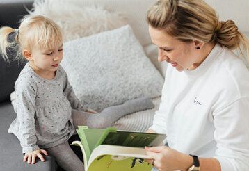 Mutter liest Tochter aus Buch vor