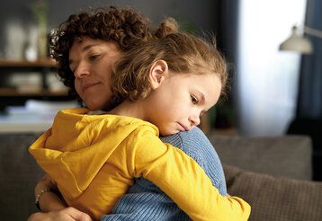 Mutter und Kind umarmen sich, beide sehen traurig aus