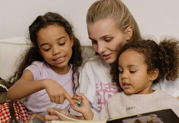 Mutter liest mit ihren zwei Töchtern ein Buch